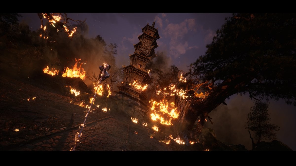 The protagonist of Black Myth: Wukong resting on a staff wit ha burning temple in the background